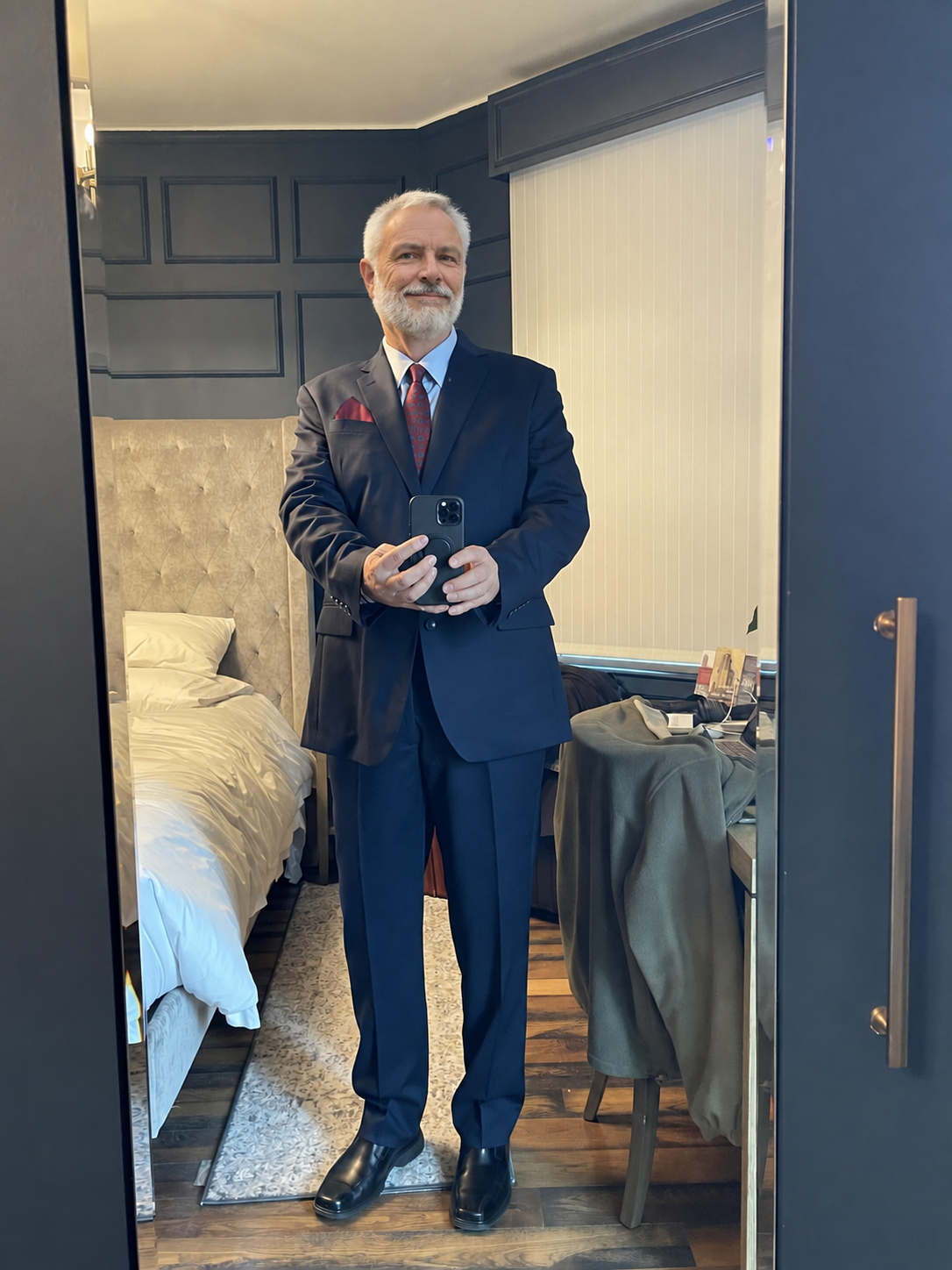 The host in a navy suit taking a mirror photograph