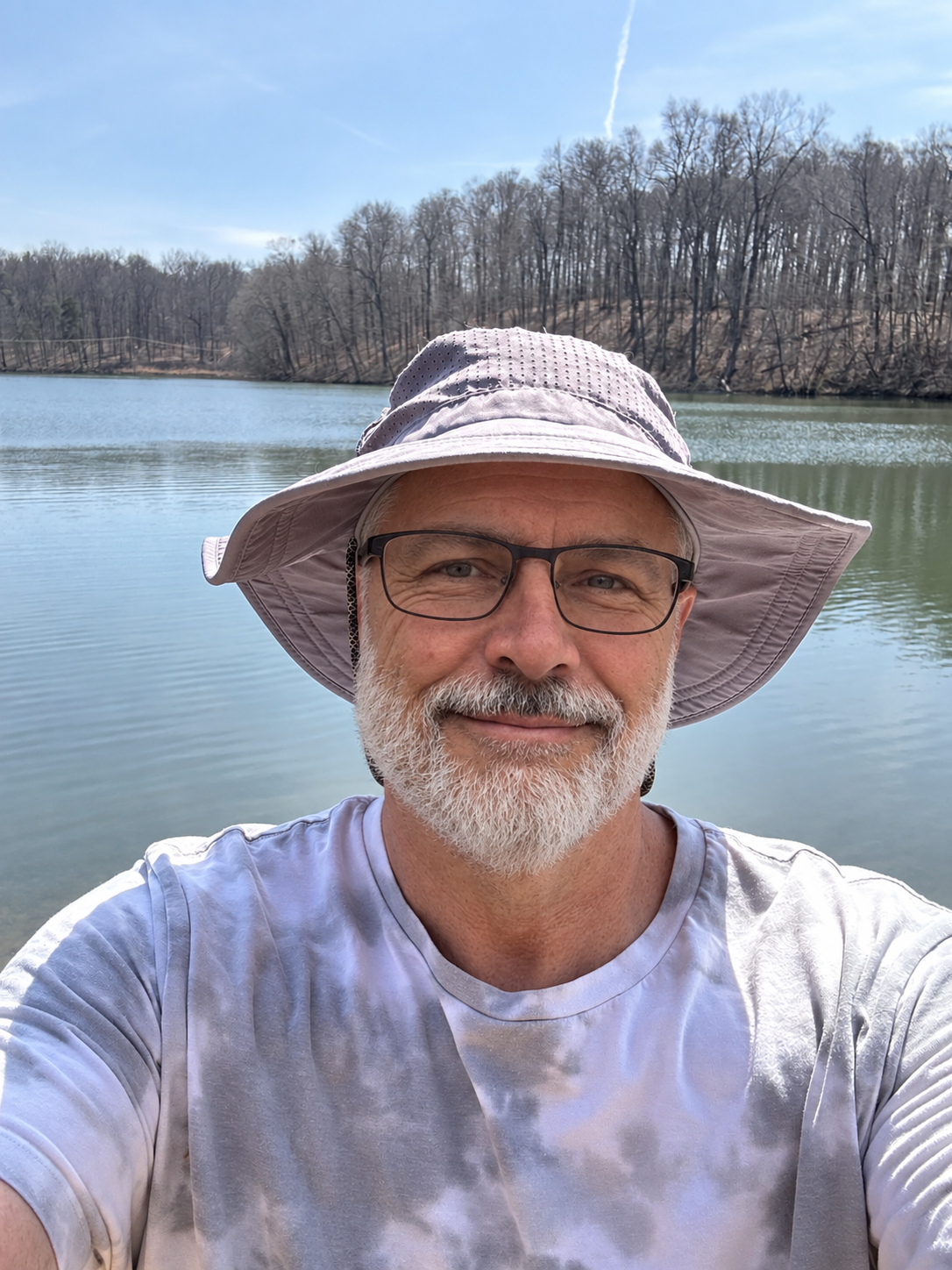 The host in a sunhat beside a lake